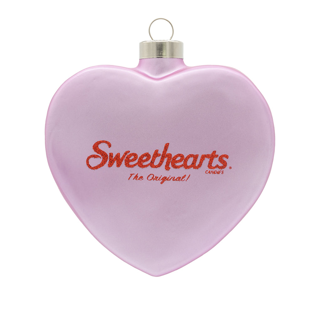 Sweethearts® CUTIE PIE Ornament. A pink Sweethearts candy heart with the logo on it in red glitter. View of back.
