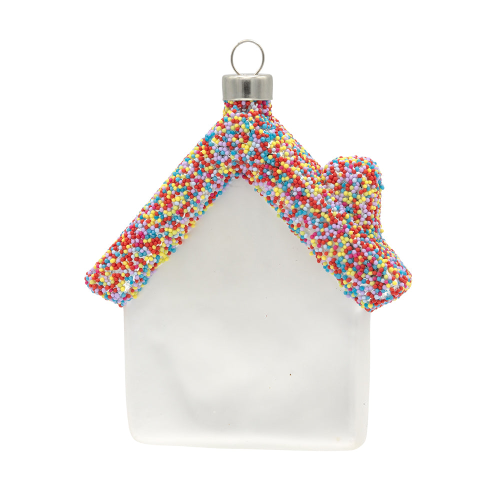 Home Sweet Home ornament. A white glass house with "HOME SWEET HOME" written in white on it. The roof is made out of rainbow sprinkles. View of back.