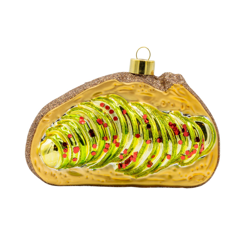Avocado Toast ornament. A slice of toast with avocado and red glitter flakes. View of front.
