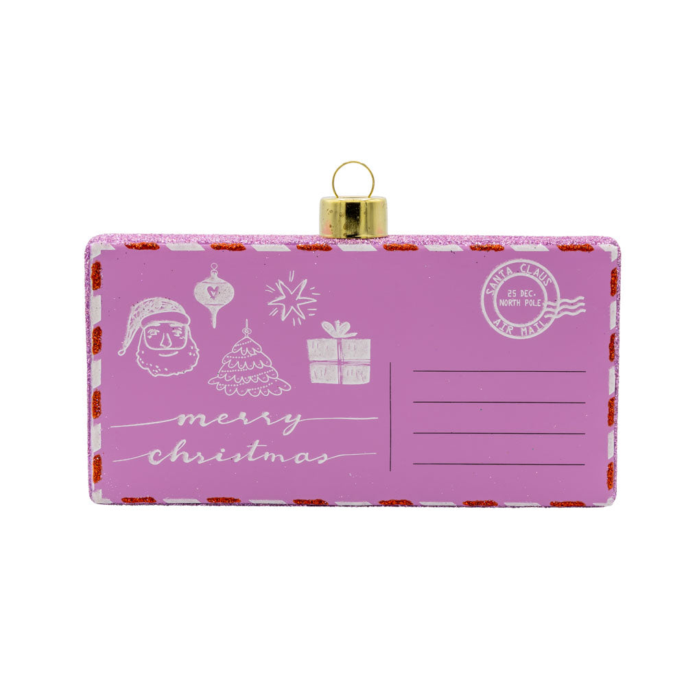 North Pole Greetings ornament. A pink post card with Christmas doodles of ornaments, Santa, and presents. View of front.