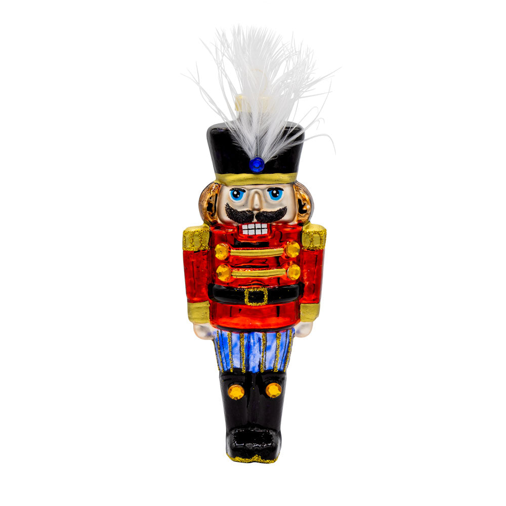 Traditional Nutcracker ornament. This nutcracker dons a red coat and feather in his hat. View of front.