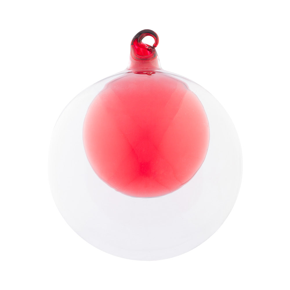 A radiant red ornament is housed within a larger transparent glass round creating added depth for this stunning ornament.